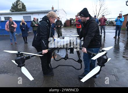 Litovel, Tschechische Republik. Dezember 2024. DJI Agras T50 Drohne, die für die effektive Anwendung von Mückensprays in Dörfern in der Nähe des Naturschutzgebiets Litovelske Pomoravi, Litovel, Region Olomouc, 10. Dezember 2024 verwendet wird. Die Drohne ist mit modernster Technologie ausgestattet und ermöglicht den Einsatz von flüssigen oder streuenden Mitteln in der Landwirtschaft. Auf dem Foto Jiri Smola, links, und Tomas Mrva, Techniker der Zulieferfirma, passen die Ausrichtung der Drohne vor dem Start an. Quelle: Ludek Perina/CTK Photo/Alamy Live News Stockfoto