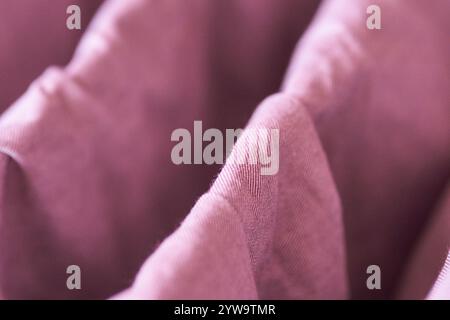 Nahaufnahme aus weichem rosa Stoff mit drapierten Falten, die ein strukturiertes abstraktes Muster erzeugen. Stockfoto