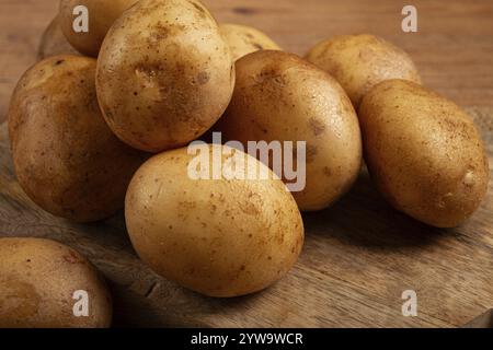 Rohe Kartoffeln, verstreut auf einem Schneidebrett, Nahaufnahme, keine Leute Stockfoto