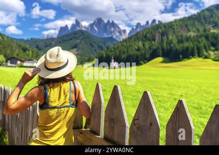 Weibliche Touristen mit Strohhut, die den atemberaubenden Blick auf die Berge und St. Magdalena-Kirche im val di funes Stockfoto