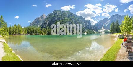 Touristen genießen das atemberaubende Panorama des pragser Sees mit seinem kristallklaren türkisfarbenen Wasser, das die majestätischen dolomiten in einem sonnigen Sommer reflektiert Stockfoto