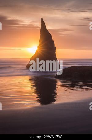 Der Sonnenuntergang am Bandon Beach besticht durch majestätische Meeresstapel, goldene Strahlen, die sich auf nassem Sand spiegeln, und ruhige Meereswellen, die eine atemberaubende und ruhige Atmosphäre schaffen Stockfoto