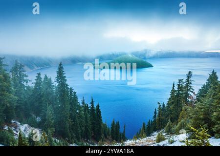 Der neblige Morgen hüllt den Crater Lake National Park in Oregon und hebt das ruhige, tiefblaue Wasser, den immergrünen Wald und die berühmte Insel hervor. erzeugen eines Stockfoto