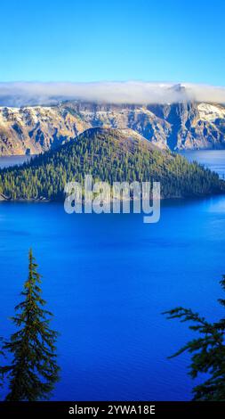 Vormittag im Crater Lake National Park in Oregon, mit Blick auf das ruhige, tiefblaue Wasser, den immergrünen Wald und die berühmte Insel, ein ruhiges und Stockfoto