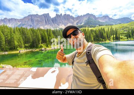 Touristen, die den atemberaubenden Blick auf den karersee und die dolomiten genießen, Selfie machen und Daumen hoch halten Stockfoto