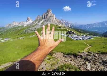 Männlicher Tourist zeigt fünf Finger mit dem majestätischen Nuvolau-Gipfel und dem passo giau-Pass im Hintergrund an einem sonnigen Sommertag Stockfoto