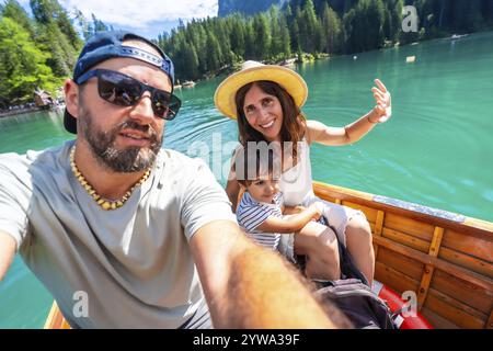 Glückliche Familie mit einem Kind, das ein Selfie macht, während Sie im Sommer eine Bootsfahrt auf dem wunderschönen pragser See in den dolomiten, italien, genießen Stockfoto