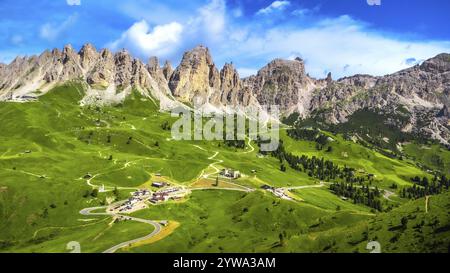 Atemberaubende Aussicht auf den malerischen gardena Pass, der sich durch üppig grüne Täler schlängelt, umgeben von den majestätischen Gipfeln der dolomiten unter einem leuchtenden Blau Stockfoto