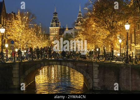 Fahrräder parken auf einer nächtlichen Brücke über einen Kanal, Amsterdam, Niederlande Stockfoto