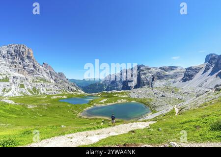 Atemberaubende Aussicht auf die Tre cime di lavaredo und die umliegenden Seen mit einem Touristen, der den sonnigen Sommertag in den dolomiten genießt. Laghi dei Piani Stockfoto