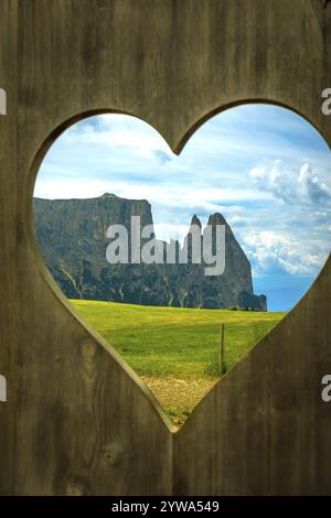 Atemberaubende Aussicht auf die dolomiten durch eine herzförmige Öffnung in einem Holzzaun auf der seiser alm, die die Schönheit des italienischen A zeigt Stockfoto