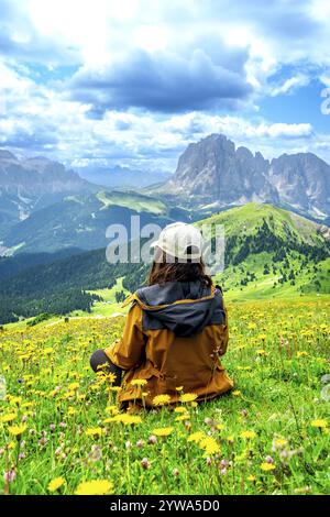 Wanderer, der sich auf einer Wiese mit gelben Blumen entspannt und die edlen Berge in den italienischen dolomiten bewundert Stockfoto