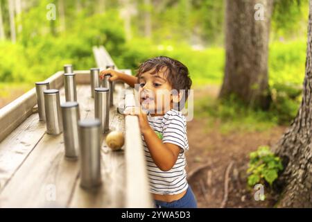 Kleinkinder erkunden und interagieren mit einer sensorischen Spielstation in einem Naturpark und genießen Outdoor-Aktivitäten Stockfoto