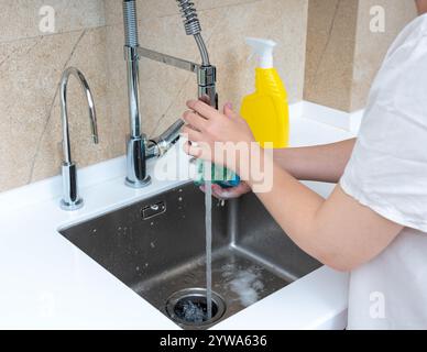 Geschirrspüler in einem modernen Spülbecken mit fließendem Wasser und Seife. Stockfoto