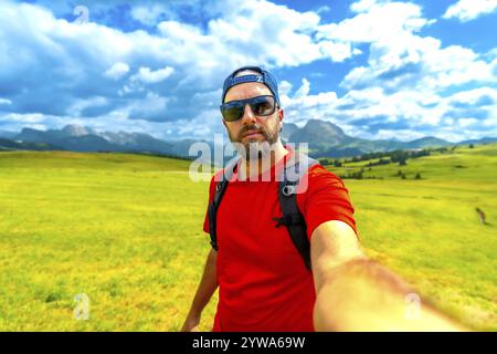 Ein Tourist trägt eine Sonnenbrille und eine Baseballmütze und macht an einem schönen Sommertag ein Selfie gegen die atemberaubenden dolomiten Stockfoto