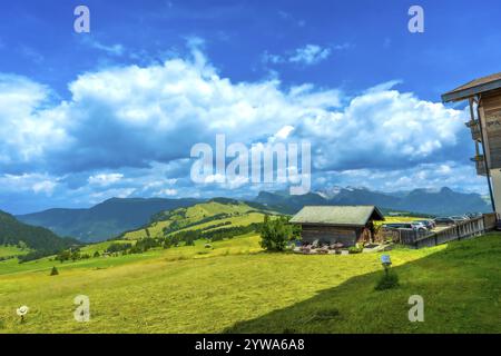Atemberaubende Landschaft, die die Schönheit der seiser alm mit grünen Wiesen, traditionellen Holzhütten und majestätischen Bergen unter einem leuchtend blauen Himmel zeigt Stockfoto