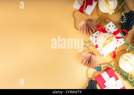 Weihnachtlicher flacher Hintergrund im gemütlichen nordischen Hygge-Stil, Komposition mit traditionellen skandinavischen Papier-Wabenornamenten, Geschenkboxen, goldener Granat Stockfoto