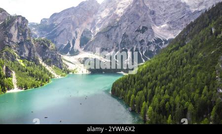 Türkisfarbenes Wasser und üppige Wälder umgeben den pragser See mit Touristen, die an einem wunderschönen Sommertag in den dolomiten Kajakfahren Stockfoto