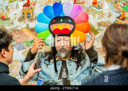 London, Großbritannien. Dezember 2024. Der Künstler, mit seinem stets präsenten Social-Media-Team, vor Gion Sairei-zu Takashi Murakami Ver., 2024 - Japanische Kunstgeschichte à la Takashi Murakami eine neue Ausstellung von Takashi Murakami, seine größte Ausstellung in London seit 15 Jahren, im Gagosian Grosvenor Hill, London. Es bietet seine eigenen Neuinterpretationen einiger der wichtigsten Kunstwerke der japanischen Kunstgeschichte, wobei KI-generierte Bilder mit handgemalten Elementen kombiniert werden. Er übernahm auch den Gagosian Gallery Shop in Burlington Arcade, um zweihundert T-Shirts in limitierter Auflage zu veröffentlichen, die der Künstler entworfen hatte. Stockfoto