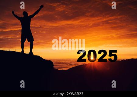 Der Mann auf dem Gipfel des Berges beobachtet den Sonnenuntergang von 2024 und den Sonnenaufgang des neuen Jahres 2025 Stockfoto