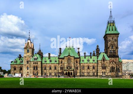 Ein großes Gebäude mit einem grünen Dach und einem Uhrenturm. Das Gebäude ist von einer Grasfläche umgeben Stockfoto