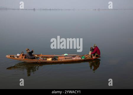 Srinagar, Jammu Und Kaschmir, Indien. Dezember 2024. Ein Kaschmir-Bootsmann bringt indische Touristen an einem kalten und nebeligen Wintermorgen in Srinagar über den weltberühmten Dal-See. Im Kaschmir-Tal herrschte intensive Kälte, da die Mindesttemperatur mehrere Grad unter den Gefrierpunkt fiel. Die Hauptstadt der Region Srinagar verzeichnet die kälteste Nacht der Saison bei minus 5,4 Grad Celsius (41,72 Grad Fahrenheit), berichteten Wetterbeamte in der Himalaya-Region. (Credit Image: © Faisal Bashir/SOPA Images via ZUMA Press Wire) NUR REDAKTIONELLE VERWENDUNG! Nicht für kommerzielle ZWECKE! Stockfoto