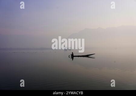 Srinagar, Jammu Und Kaschmir, Indien. Dezember 2024. Ein kaschmirischer Bootsmann rudert sein Boot an einem kalten und nebeligen Wintermorgen in Srinagar über den weltberühmten Dal-See. Im Kaschmir-Tal herrschte intensive Kälte, da die Mindesttemperatur mehrere Grad unter den Gefrierpunkt fiel. Die Hauptstadt der Region Srinagar verzeichnet die kälteste Nacht der Saison bei minus 5,4 Grad Celsius (41,72 Grad Fahrenheit), berichteten Wetterbeamte in der Himalaya-Region. (Credit Image: © Faisal Bashir/SOPA Images via ZUMA Press Wire) NUR REDAKTIONELLE VERWENDUNG! Nicht für kommerzielle ZWECKE! Stockfoto