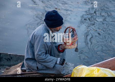 Srinagar, Jammu Und Kaschmir, Indien. Dezember 2024. Ein Mann aus Kaschmir bläst Holzkohle, um sie in einem Feuertopf oder Kangri an einem kalten und nebeligen Wintermorgen in Srinagar anzuzünden. Im Kaschmir-Tal herrschte intensive Kälte, da die Mindesttemperatur mehrere Grad unter den Gefrierpunkt fiel. Die Hauptstadt der Region Srinagar verzeichnet die kälteste Nacht der Saison bei minus 5,4 Grad Celsius (41,72 Grad Fahrenheit), berichteten Wetterbeamte in der Himalaya-Region. (Credit Image: © Faisal Bashir/SOPA Images via ZUMA Press Wire) NUR REDAKTIONELLE VERWENDUNG! Nicht für kommerzielle ZWECKE! Stockfoto