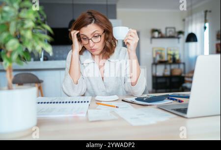 Schöne nachdenkliche Frau mittleren Alters in Brille mit monatlichen Rechnungen, die über das Budget für das Familienheim nachdenken. Kleine Unternehmen, Hausfinanzen, Spargelder Stockfoto