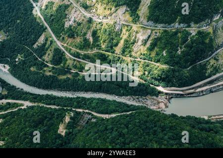Blick von oben auf den sich windenden Fluss durch das üppige grüne Bergtal mit kurvigen Straßen, steilen Hängen und dichter Waldvegetation. Stockfoto