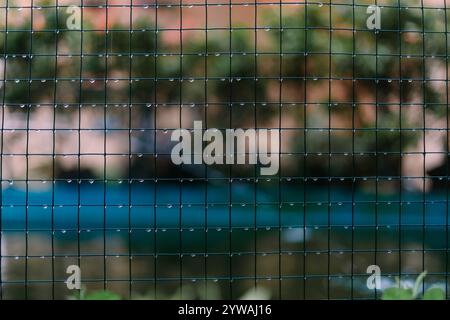 Von Regen durchtränktes Drahtgeflecht mit Wassertropfen an der Oberfläche, die die Folgen eines regnerischen Tages in einem Industrie- oder Outdoor-Set festhalten Stockfoto