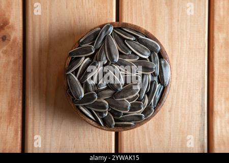 Schwarze Sonnenblumenkerne in einer Schüssel auf Holzgrund Stockfoto