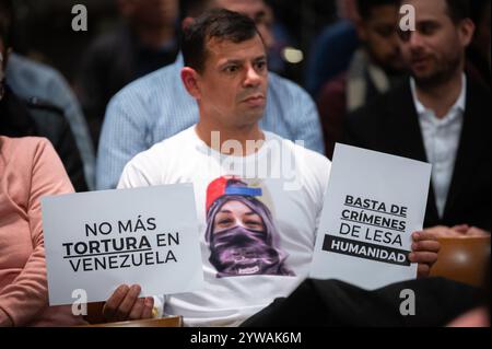 Madrid, Spanien. Dezember 2024. Ein Mann trägt Plakate, um während der Konferenz "die Herausforderung der Befreiung in Venezuela: Menschenrechte, Gerechtigkeit und Demokratie" zu protestieren. Quelle: Marcos del Mazo/Alamy Live News Stockfoto