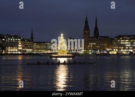 Hamburg, Deutschland. Dezember 2024. Eine Ruderacht segelt am beleuchteten Weihnachtsbaum auf der inneren Alster vorbei. Quelle: Marcus Brandt/dpa/Alamy Live News Stockfoto