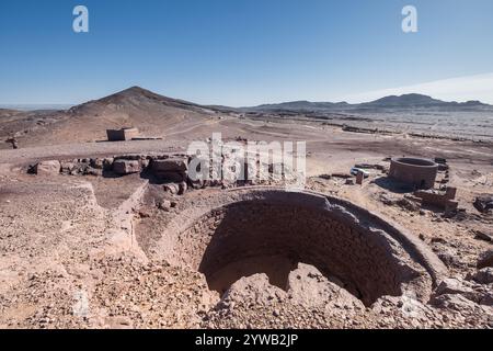 Panoramablick auf den alten Meeresboden der schwarzen Wüste von Marokko mit einem alten tiefen und großen Brunnenbau in der Nähe der alten verlassenen Fossilienmine. Stockfoto