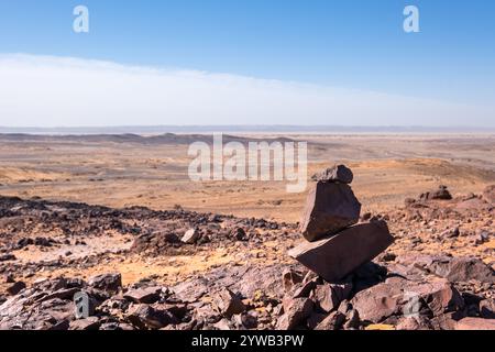 Panoramablick auf den alten Meeresboden der schwarzen Wüste von Marokko mit der Nähe der alten verlassenen Fossilienmine. Es gibt eine ausgeglichene Felsskulptur Stockfoto