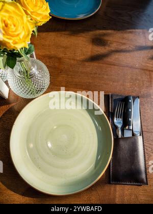 Draufsicht auf leere grüne Keramikplatte und Servierutensilien auf braunem Tisch Stockfoto