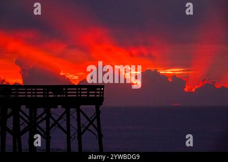 Isle Of Palms, Usa. Dezember 2024. Der Sonnenaufgang bricht hinter schweren Wolken, als eine Front durch das niedere Land schiebt, wodurch die Sonne über dem Atlantischen Ozean am Front Beach aufgeht, 10. Dezember 2024 in Isle of Palms, South Carolina. Das warme und feuchte Wetter weicht später in der Woche einer kalten Front. Quelle: Richard Ellis/Richard Ellis/Alamy Live News Stockfoto