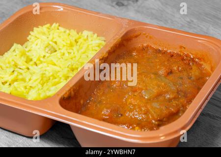 Hühnchen balti indisches heißes scharfes Curry Fertiggericht TV-Abendessen in Plastikverpackung. Auf einem Holzbrett Stockfoto