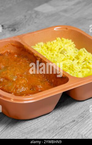 Hühnchen balti indisches heißes scharfes Curry Fertiggericht TV-Abendessen in Plastikverpackung. Auf einem Holzbrett Stockfoto