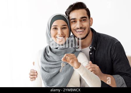 Glückliche arabische Familie umarmt und zeigt den Wohnungsschlüssel Stockfoto