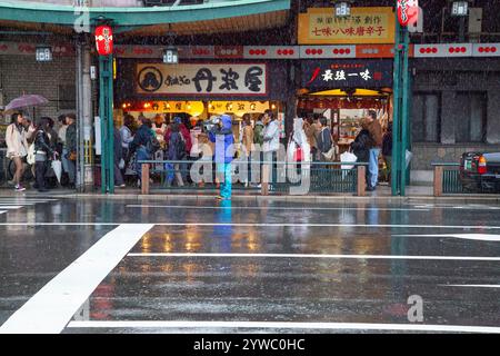 Szene mit Menschen und Verkehr auf der Shijo Street in der Innenstadt von Gion, Kyoto, Japan bei Regen. Stockfoto