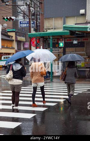 Ältere japanische Frauen tragen Kimonos im Regen auf der Shijo Street in der Innenstadt von Gion, Kyoto, Japan Stockfoto