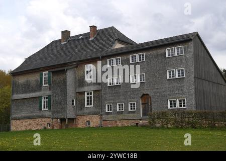 Traditionelles schieferverkleidetes Bauernhaus mit Holzdetails, Steinfundament und mehreren Fenstern, Stockfoto