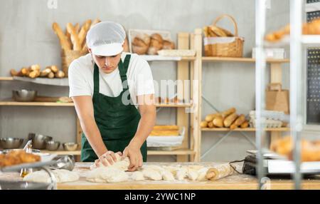 Junge Bäcker kneten den Teig in der Bäckerei Stockfoto