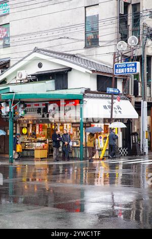 Szene mit Menschen und Verkehr auf der Shijo Street in der Innenstadt von Gion, Kyoto, Japan bei Regen. Stockfoto