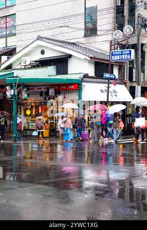 Szene mit Menschen und Verkehr auf der Shijo Street in der Innenstadt von Gion, Kyoto, Japan bei Regen. Stockfoto