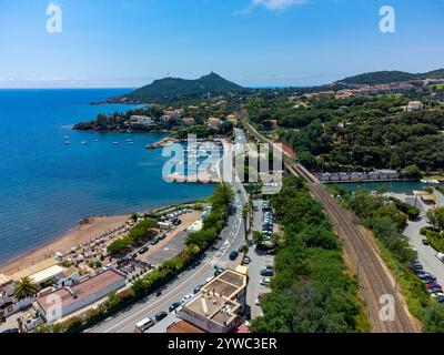 Panoramablick von oben auf das blaue Mittelmeer dea, Sandstrand der Stadt Agay, Sommerferienziel in der Nähe der roten Berge von Esterel, französische Riviera, Stockfoto