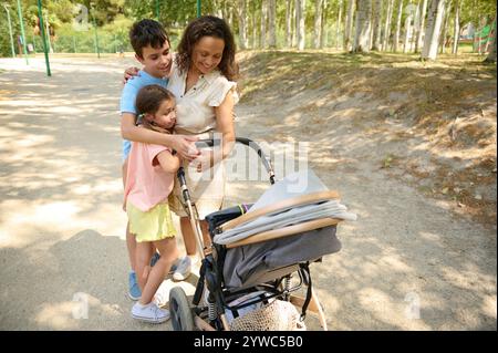 Eine fröhliche Familie genießt einen sonnigen Tag im Park und schlendert mit einem Kinderwagen. Die Atmosphäre ist hell und voller Wärme und Zuneigung Stockfoto