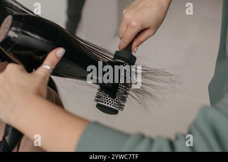 Nahaufnahme eines Friseurs, der lange Haare einer Frau trocknet Stockfoto